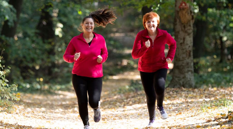 Matka i córka ubrane w strój sportowy i biegające w lesie