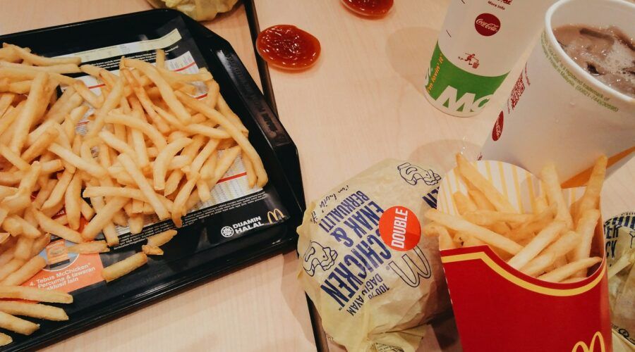 Niezdrowa dieta - duża ilość frytek i podwójny hamburger leżące na stole